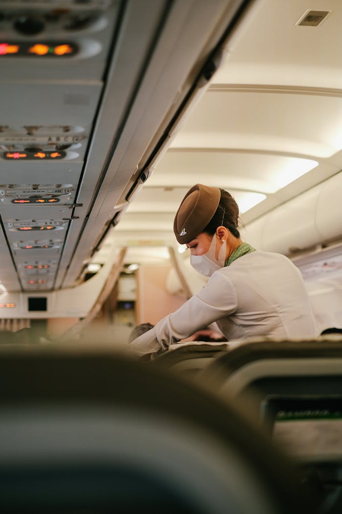 A flight attendant performs duties onboard a passenger airplane while wearing a protective mask.